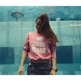 Różowy sweter z napisem NO MORE FEARS, modna stylizacja z jeansami, kobieta w basenie