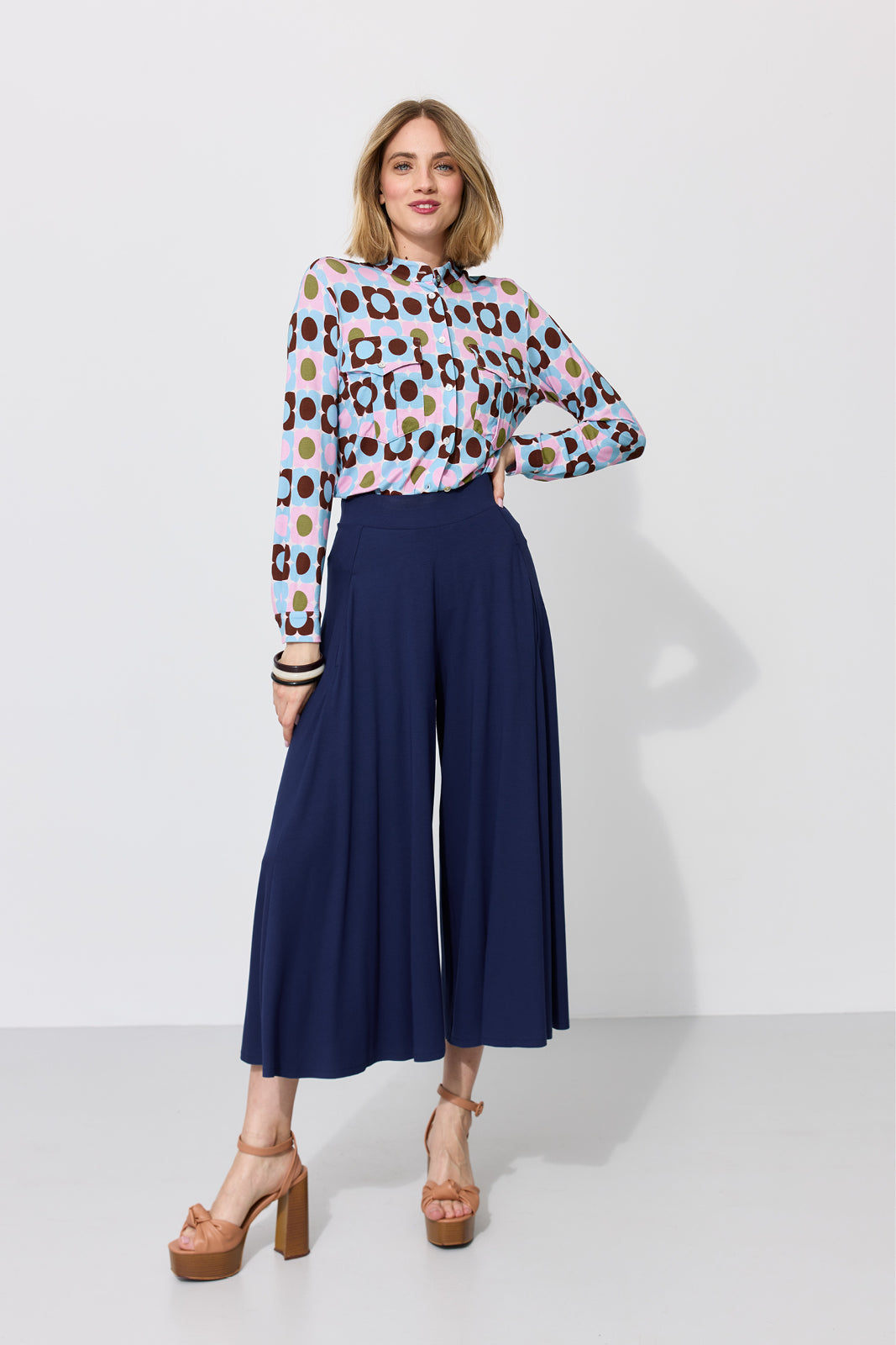Kobieta w kolorowej koszuli z geometrycznym wzorem i granatowych spodniach culottes, stylowy strój na co dzień