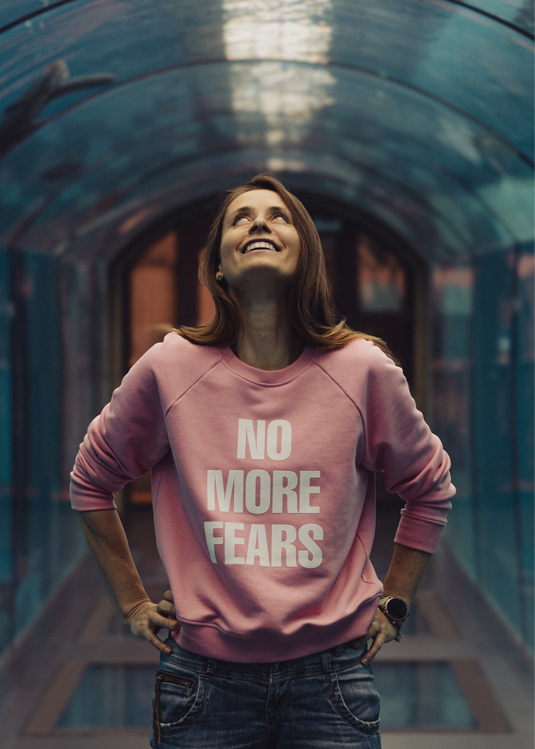 Różowy sweter z napisem NO MORE FEARS, modna stylizacja z jeansami, self-care fashion