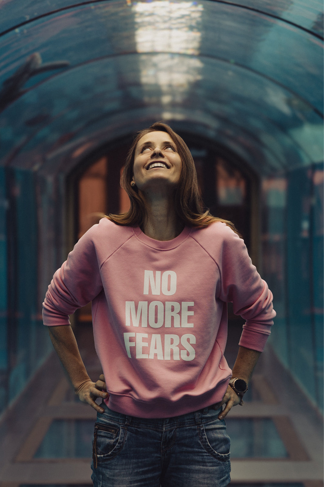 Różowy sweter z napisem NO MORE FEARS, modna stylizacja z jeansami, self-care fashion