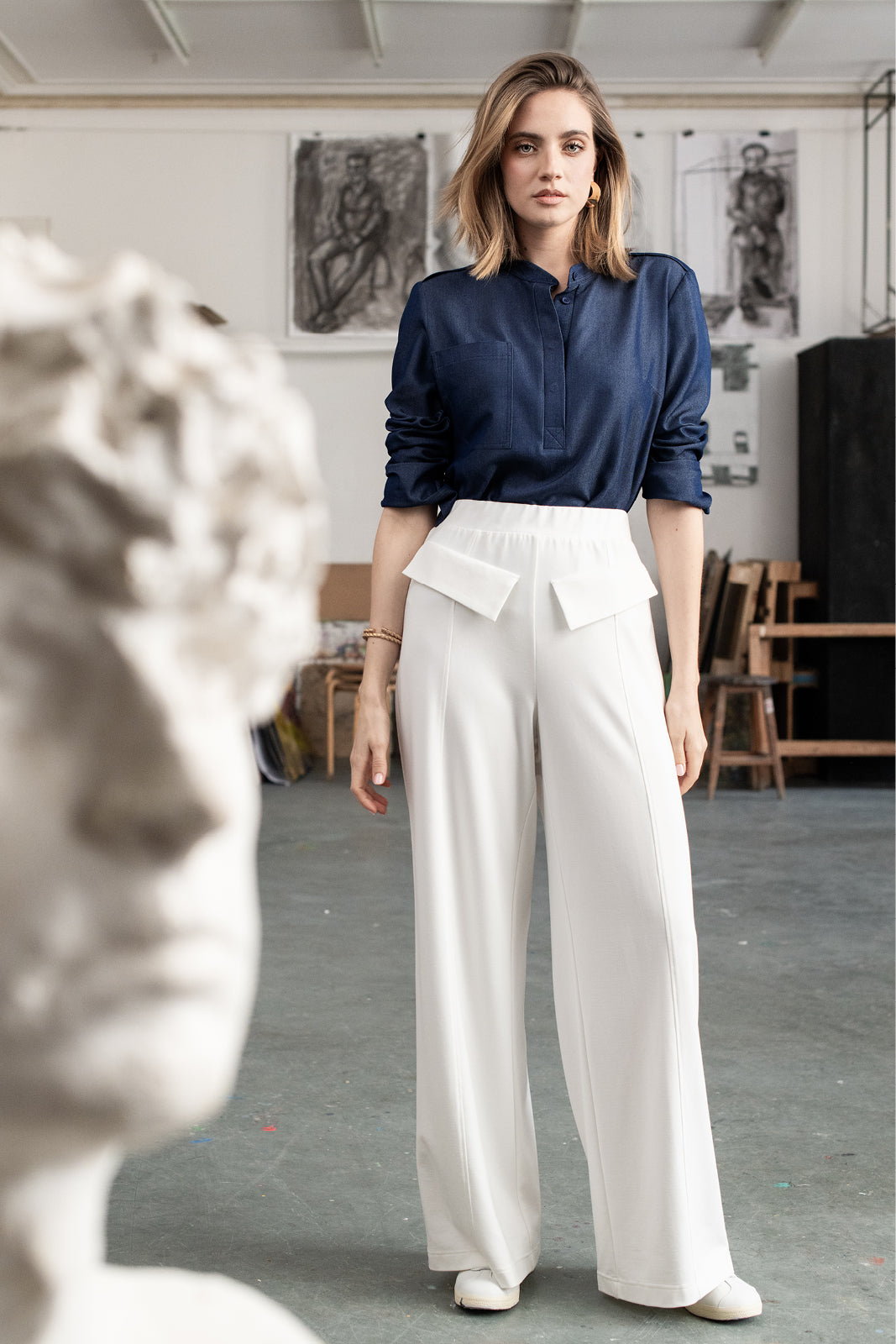 Kobieta w białych spodniach wide leg i granatowej bluzie z kieszenią, stylowa stylizacja na co dzień