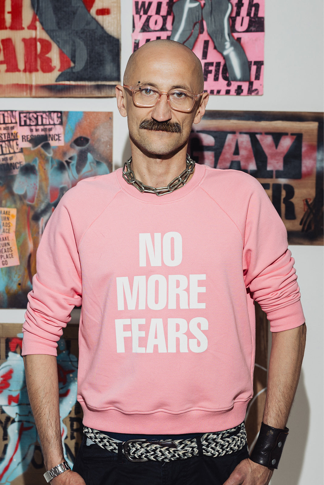 Różowy sweter z napisem NO MORE FEARS, stylowy strój z łańcuszkiem i pasem, moda z kulturą i wygodą