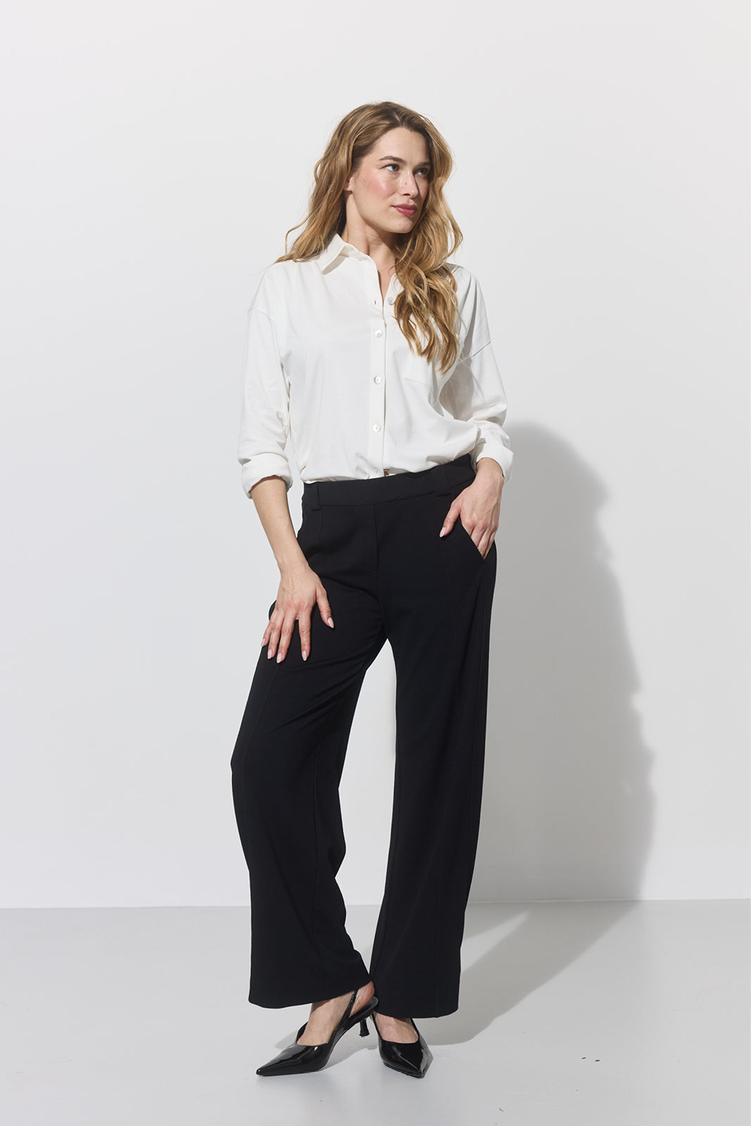 Kobieta w białej koszuli i czarnych spodniach wide leg – elegancka stylizacja na co dzień z precyzyjnym krojem